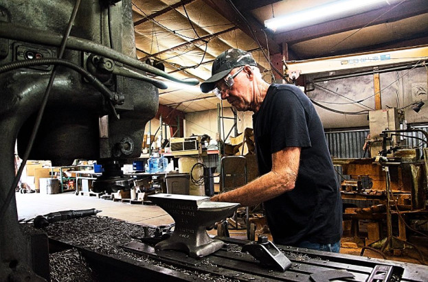 Cliff Carroll secures an anvil to a grinder at his Larkspur, CO., shop. Photo credit: American Farriers Journal.